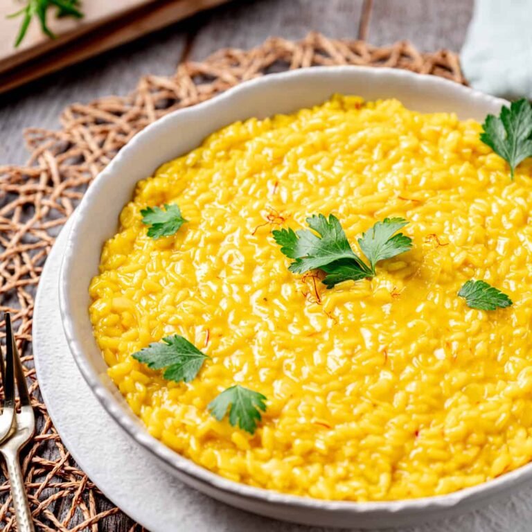 Creamy homemade saffron risotto recipe served in a bowl with parmesan cheese and saffron garnish.