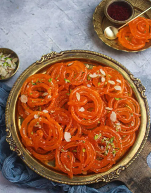 Crispy homemade jalebi recipe served fresh with sugar syrup on a traditional plate