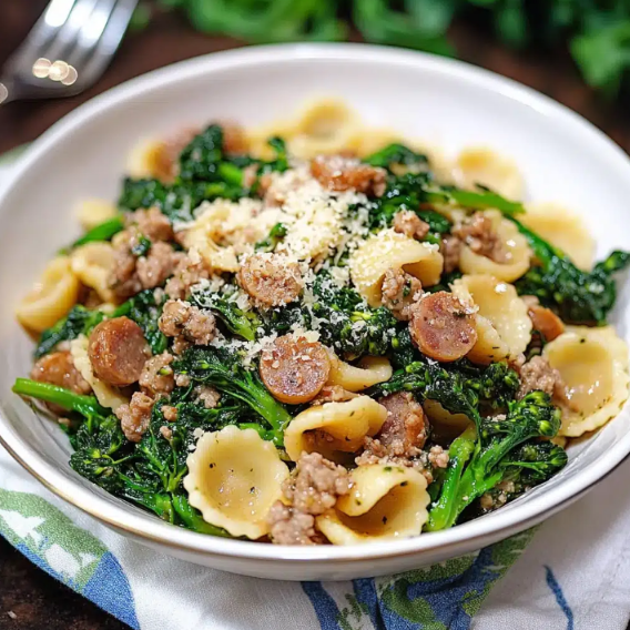 A bowl of broccoli rabe and sausage featuring tender rapini, juicy Italian sausage, garlic, and grated Parmesan cheese