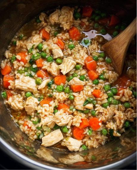 A bowl of homemade Instant Pot Chicken and Rice with tender chicken, fluffy rice, carrots, peas, and fresh parsley.