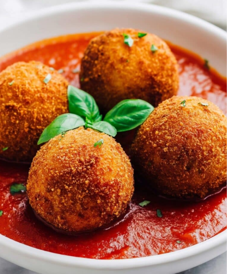 Golden cheesy rice ball arancini with a crispy breadcrumb coating and melted mozzarella center
